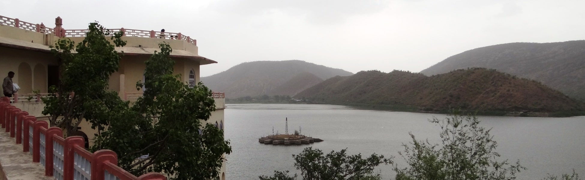 Panoramic view of the historic Siliserh Lake Palace balcony looking out over Siliserh Lake and the surrounding Aravalli hills on an overcast day in Alwar, Rajasthan, India. fixer in Balod, film fixer in Balod, media fixer in Balod, movie fixer in Balod, production fixer in Balod, line producer in Balod