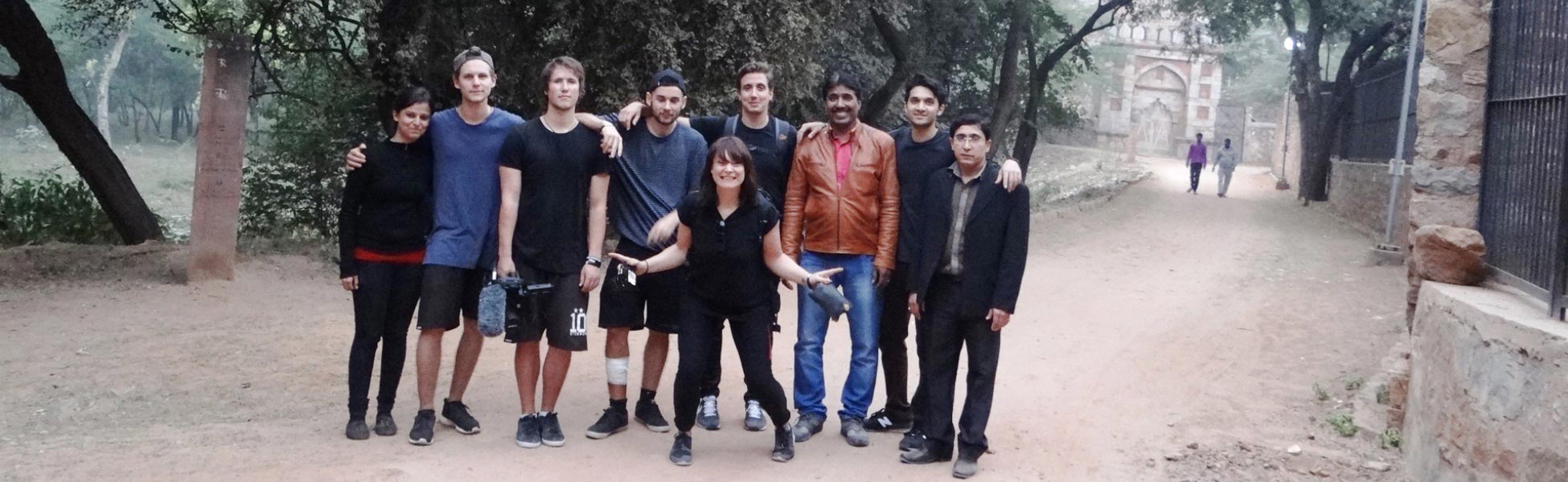 Group photo of the Trisna Films® local team and visiting UK film crew on location in New Delhi, India. The team is posing with camera and audio equipment near a historic archway during the production of Insight TV's adventure documentary series, 'Running The World'. film shooting locations in Shimla, video shooting locations in Shimla, tv shooting locations in Shimla, shooting locations in Shimla