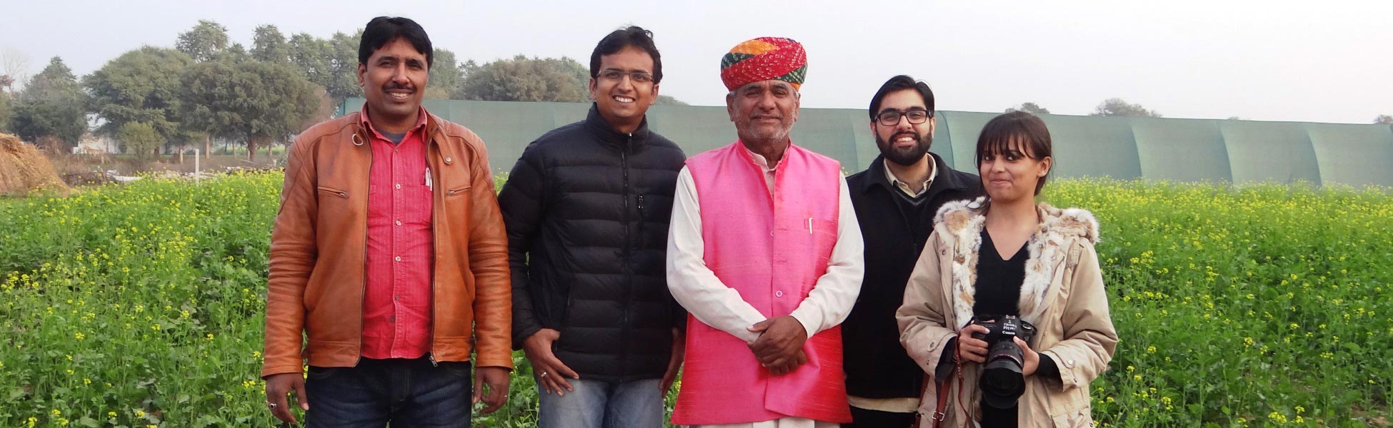 Trisna Films® and THB corporate video production crew on location in rural Rajasthan, India, standing in a field of yellow mustard flowers with a professional camera. film production house in india, film production house in Delhi, film production house in mumbai, film production house in pune, film production house in sonipat, film production house in begusarai, video production house in india, video production house in Delhi, video production house in mumbai, video production house in pune, video production house in sonipat, video production house in begusarai, tv production house in india, tv production house in delhi, tv production house in mumbai, tv production house in pune, tv production house in sonipat, tv production house in begusarai, production house in india, production house in delhi, production house in mumbai, production house in pune, production house in sonipat, production house in begusarai, film production company in india, film production company in delhi, film production company in mumbai, film production company in pune, film production company in sonipat, film production company in begusarai, video production company in india, video production company in delhi, video production company in mumbai, video production company in pune, video production company in sonipat, video production company in begusarai, tv production company in india, tv production company in delhi, tv production company in mumbai, tv production company in pune, tv production company in sonipat, tv production company in begusarai, production company in india, production company in delhi, production company in mumbai, production company in pune, production company in sonipat, production company in begusarai