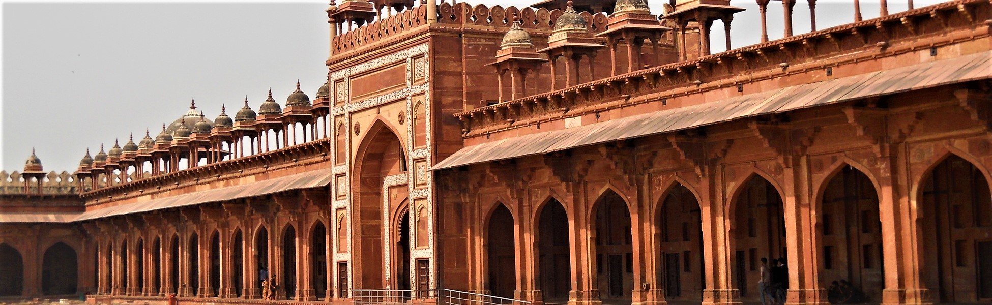 Symmetrical red sandstone arched corridors and decorative chhatris of the historic Jama Masjid courtyard at Fatehpur Sikri, a premier Mughal-era film shooting location in Uttar Pradesh, India. film shooting locations in Bargarh, video shooting locations in Bargarh, tv shooting locations in Bargarh, shooting locations in Bargarh