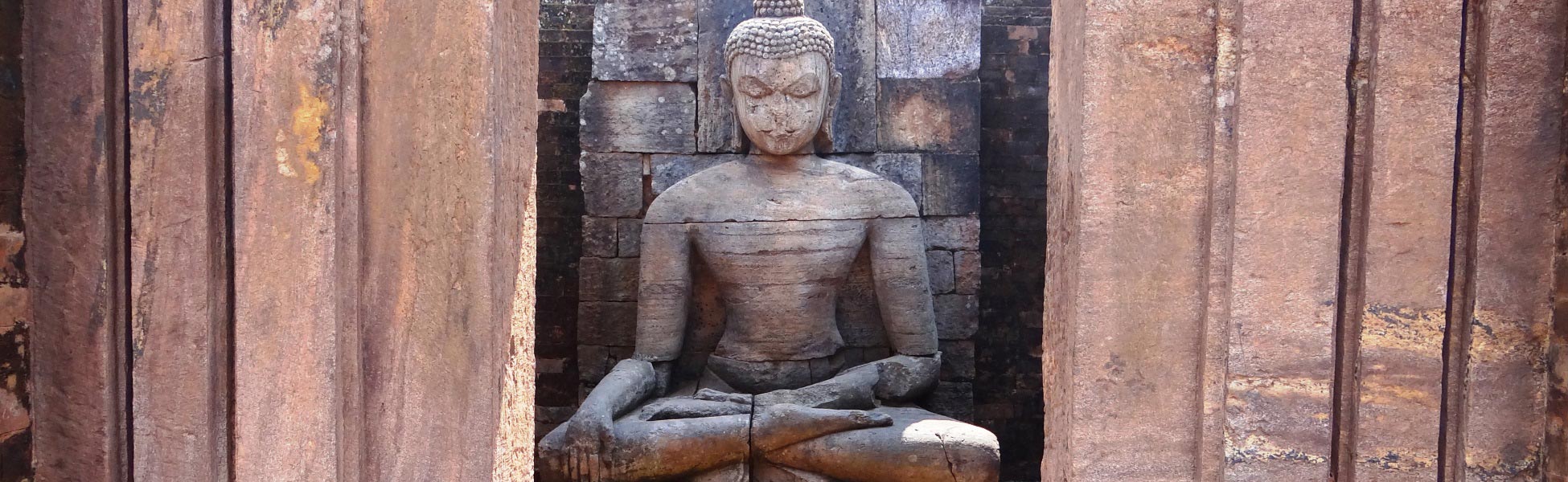 A colossal ancient stone carving of Lord Buddha seated inside a brick recess niche flanked by stone columns at the Udayagiri Buddhist monastery ruins in Jajpur district, Odisha, India—an elite cinematic location option for documentary and historical filmmakers. fixer in Bargarh, line producer in Bargarh