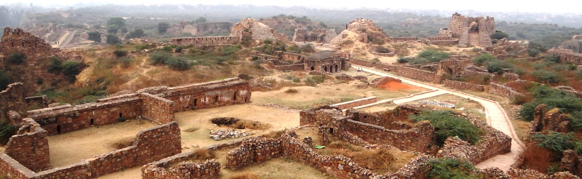Panoramic aerial view of the 14th-century stone ruins, ramparts, and weathered pathways of Tughlaqabad Fort in Delhi, India, showcasing ancient fortification architecture ideal for period film shoots. film production house in Bengaluru Urban, video production house in Bengaluru Urban, tv production house in Bengaluru Urban, production house in Bengaluru Urban, film production company in Bengaluru Urban, video production company in Bengaluru Urban, tv production company in Bengaluru Urban, production company in Bengaluru Urban