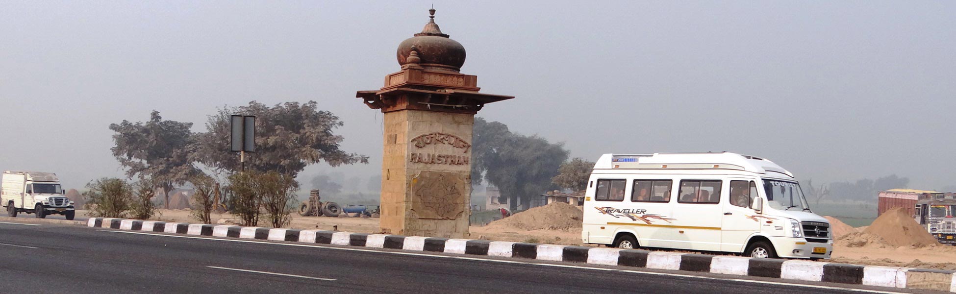 Sandstone welcome pillar with carved map marking the entry into Rajasthan state along the highway, featuring a production crew transit van on the border road. film production house in Berhampore, video production house in Berhampore, tv production house in Berhampore, production house in Berhampore, film production company in Berhampore, video production company in Berhampore, tv production company in Berhampore, production company in Berhampore