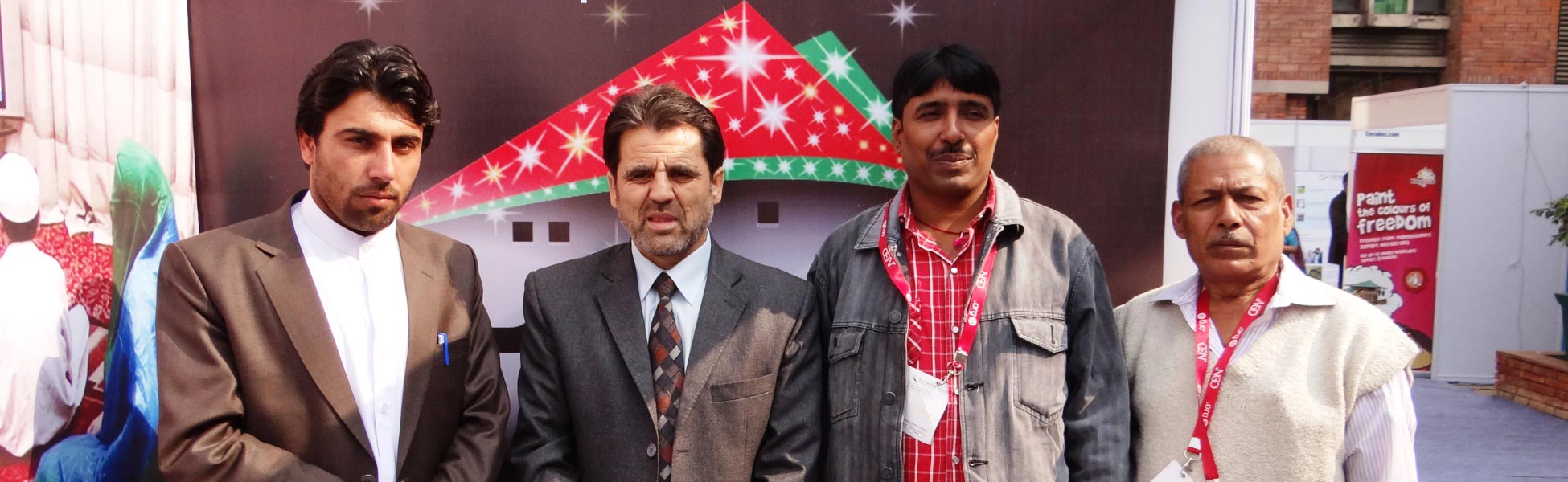 A group photo featuring DOP Avinash Kumar and an Afghan client standing before a colorful 'Paint the Colours of Freedom' backdrop during a video production event in Delhi. fixer in Bhilwara, line producer in Bhilwara