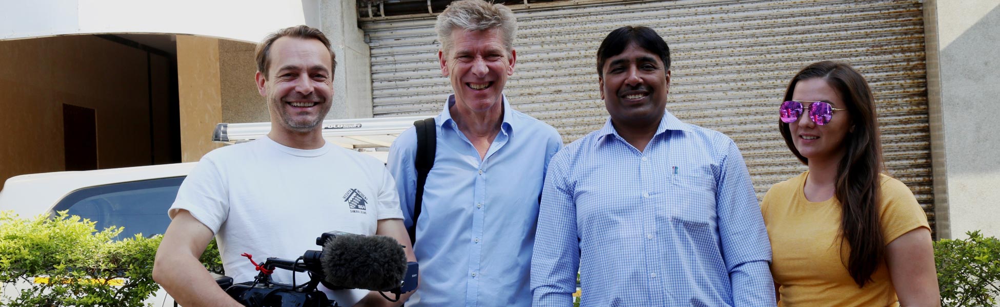 A group of four production crew members from Trisna Films® and a German TV team smiling for a photo in Mumbai. One crew member holds a professional cinema camera with a shotgun microphone, on location for the German Sat 1 travel documentary 'Grenzenlos Die Welt Entdecken'. filmmaking workshop in india, filmmaking workshop in delhi, filmmaking workshop in mumbai, filmmaking workshop in pune, filmmaking workshop in sonipat, filmmaking workshop in begusarai, cinematography workshop in india, cinematography workshop in delhi, cinematography workshop in mumbai, cinematography workshop in pune, cinematography workshop in sonipat, cinematography workshop in begusarai, camera workshop in india, camera workshop in delhi, camera workshop in mumbai, camera workshop in pune, camera workshop in sonipat, camera workshop in begusarai, editing workshop in india, editing workshop in delhi, editing workshop in mumbai, editing workshop in pune, editing workshop in sonipat, editing workshop in begusarai, vfx workshop in india, vfx workshop in Delhi, vfx workshop in mumbai, vfx workshop in pune, vfx workshop in sonipat, vfx workshop in begusarai, animation workshop in india, animation workshop in Delhi, animation workshop in mumbai, animation workshop in pune, animation workshop in sonipat, animation workshop in begusarai, photography workshop in india, photography workshop in delhi, photography workshop in mumbai, photography workshop in pune, photography workshop in sonipat, photography workshop in begusarai, direction workshop in india, direction workshop in delhi, direction workshop in mumbai, direction workshop in pune, direction workshop in sonipat, direction workshop in begusarai, script writing workshop in india, script writing workshop in delhi, script writing workshop in mumbai, script writing workshop in pune, script writing workshop in sonipat, script writing workshop in begusarai