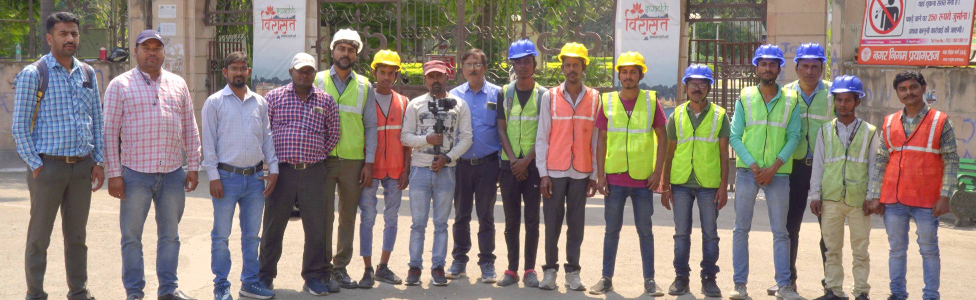 Trisna Films® and Neev Energy crew members, wearing safety gear and holding camera equipment, posing together during a corporate video production shoot for the Prayagraj Smart City project in Prayagraj, Uttar Pradesh, India. music video production house in india, music video production company in india
