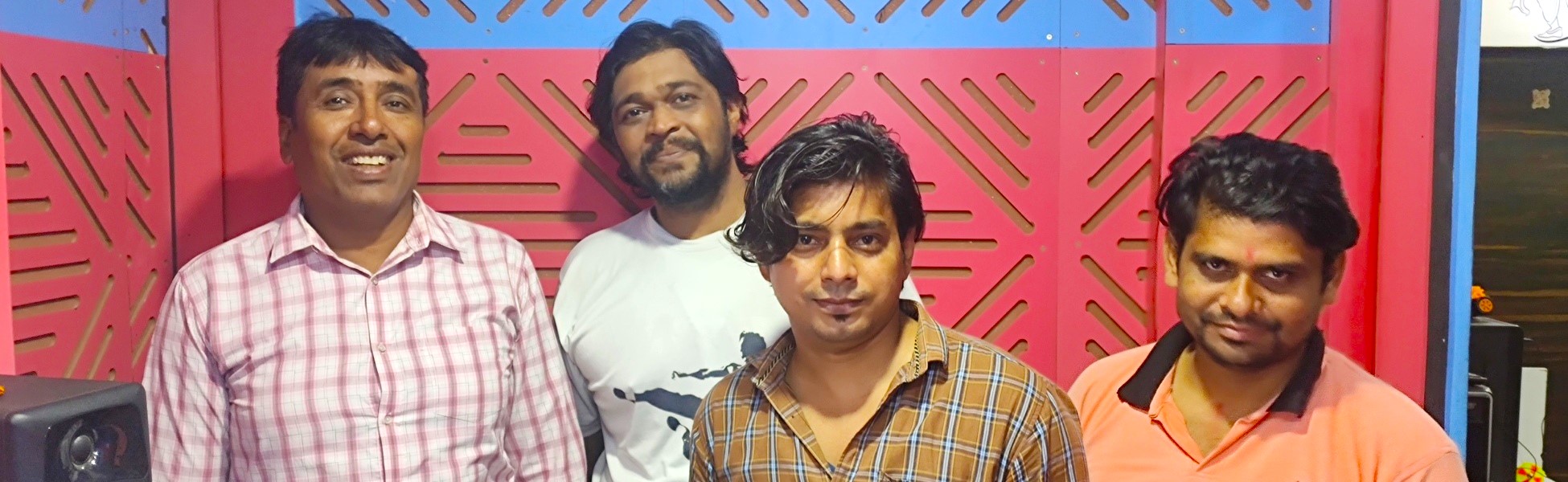 Four men, including a voice-over artist and sound engineer, posing together inside a professional audio recording studio in New Delhi. filmmaking workshop in india, cinematography workshop in india, camera workshop in india, editing workshop in india, vfx workshop in india, animation workshop in india, photography workshop in india, direction workshop in india, script writing workshop in india
