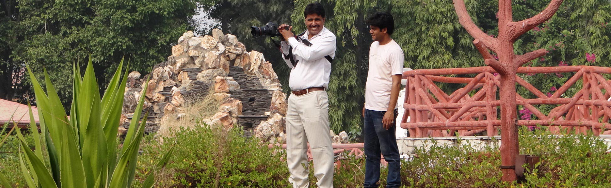 Professional cinematographers from Trisna Films® operating a DSLR rig on a lush outdoor film set. Featuring lead filmmaker capturing high-definition footage amidst tropical landscaping and rock formations for a documentary project. film production house in Aravalli, video production house in Aravalli, tv production house in Aravalli, production house in Aravalli, film production company in Aravalli, video production company in Aravalli, tv production company in Aravalli, production company in Aravalli
