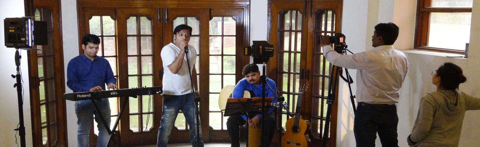 Trisna Films® production crew and musical cast filming a music video in a New Delhi studio, featuring a singer, keyboardist, and guitarist with professional camera and lighting equipment. fixer in Auraiya, film fixer in auraiya, media fixer in auraiya, movie fixer in auraiya, production fixer in auraiya, line producer in Auraiya