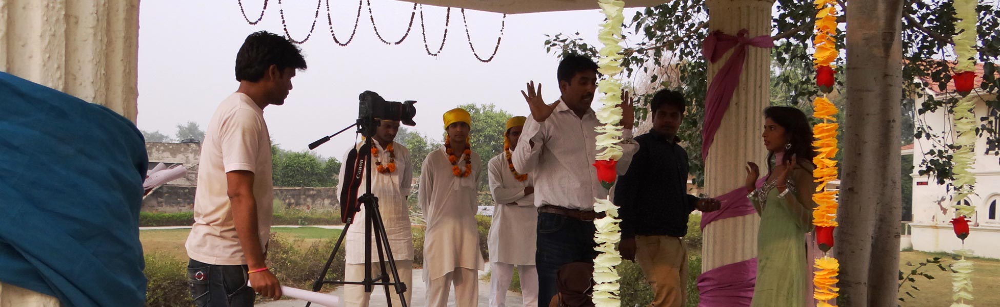Behind-the-scenes shot of a director gesturing to actors on an outdoor film set in Delhi, India, for the short film 'Andhvishwas'. A professional camera on a tripod is positioned in the foreground while actors in traditional yellow turbans wait for cues. fixer in Bagalkot, film fixer in Bagalkot, media fixer in Bagalkot, movie fixer in Bagalkot, production fixer in Bagalkot, line producer in Bagalkot