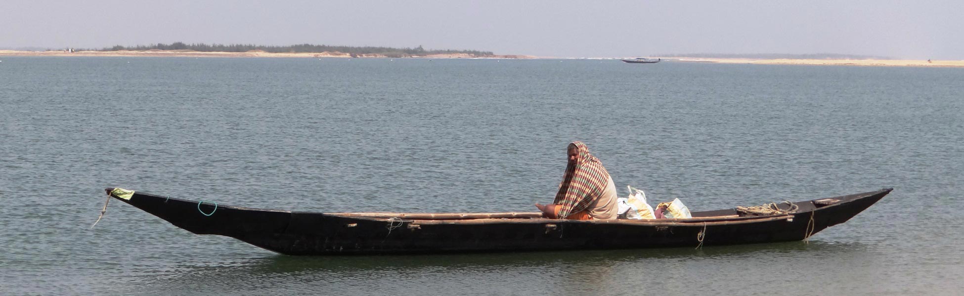 A traditional long wooden boat floating on the serene backwaters of Chilika Lake in Odisha, India—a scenic film shooting location captured by Trisna Films®. film production house in Baghpat, video production house in Baghpat, tv production house in Baghpat, production house in Baghpat, film production company in Baghpat, video production company in Baghpat, tv production company in Baghpat, production company in Baghpat