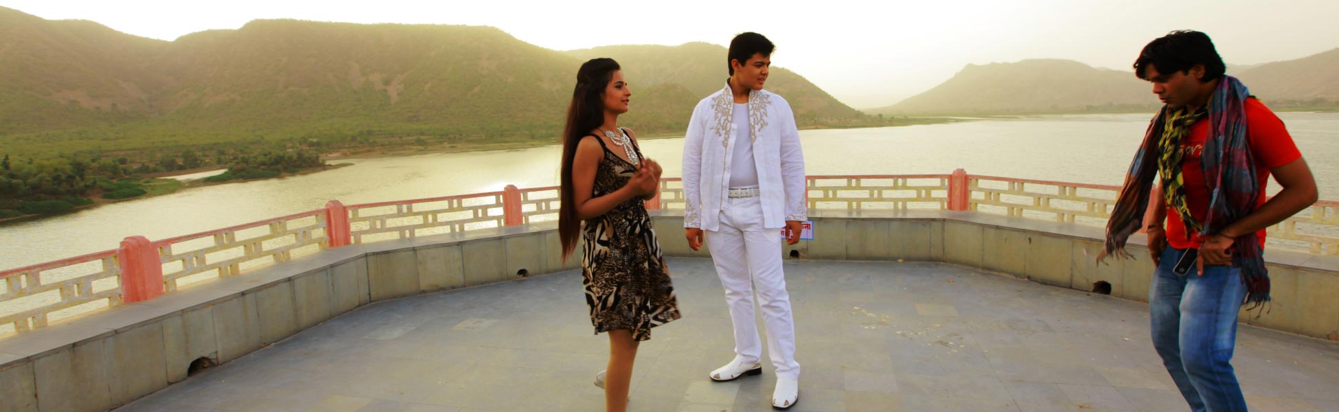 An Indian choreographer directing a male performer in a white embroidered outfit and a female performer in a patterned dress on an outdoor terrace overlooking a scenic lake and mountains during the shoot of the Indo-Uzbek music video 'Namun Chaa'. film shooting locations in Baksa, video shooting locations in Baksa, tv shooting locations in Baksa, shooting locations in Baksa