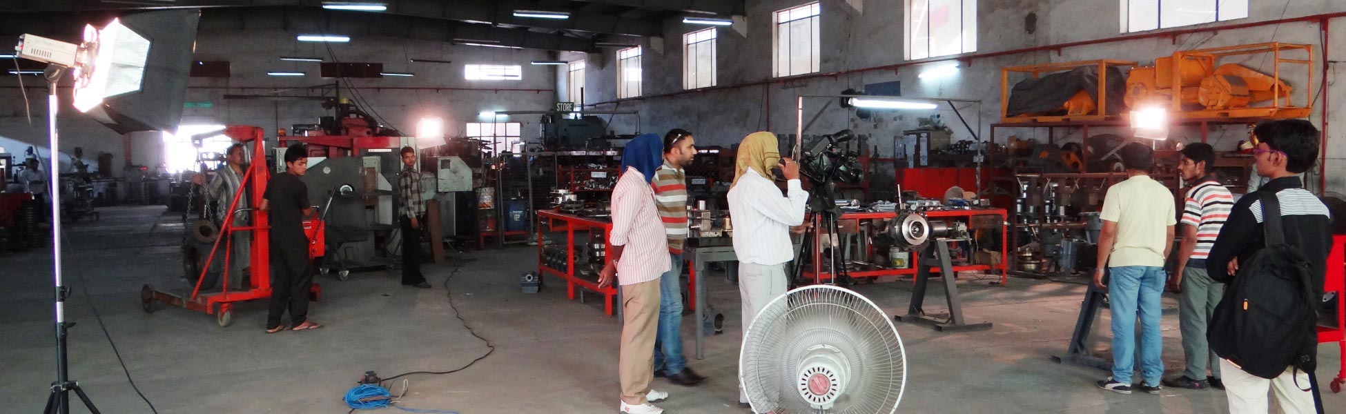 Professional camera crew and studio lighting setup filming a corporate promotional video inside an industrial manufacturing workshop floor in Ludhiana, Punjab. fixer in Balangir, film fixer in Balangir, media fixer in Balangir, movie fixer in Balangir, production fixer in Balangir, line producer in Balangir